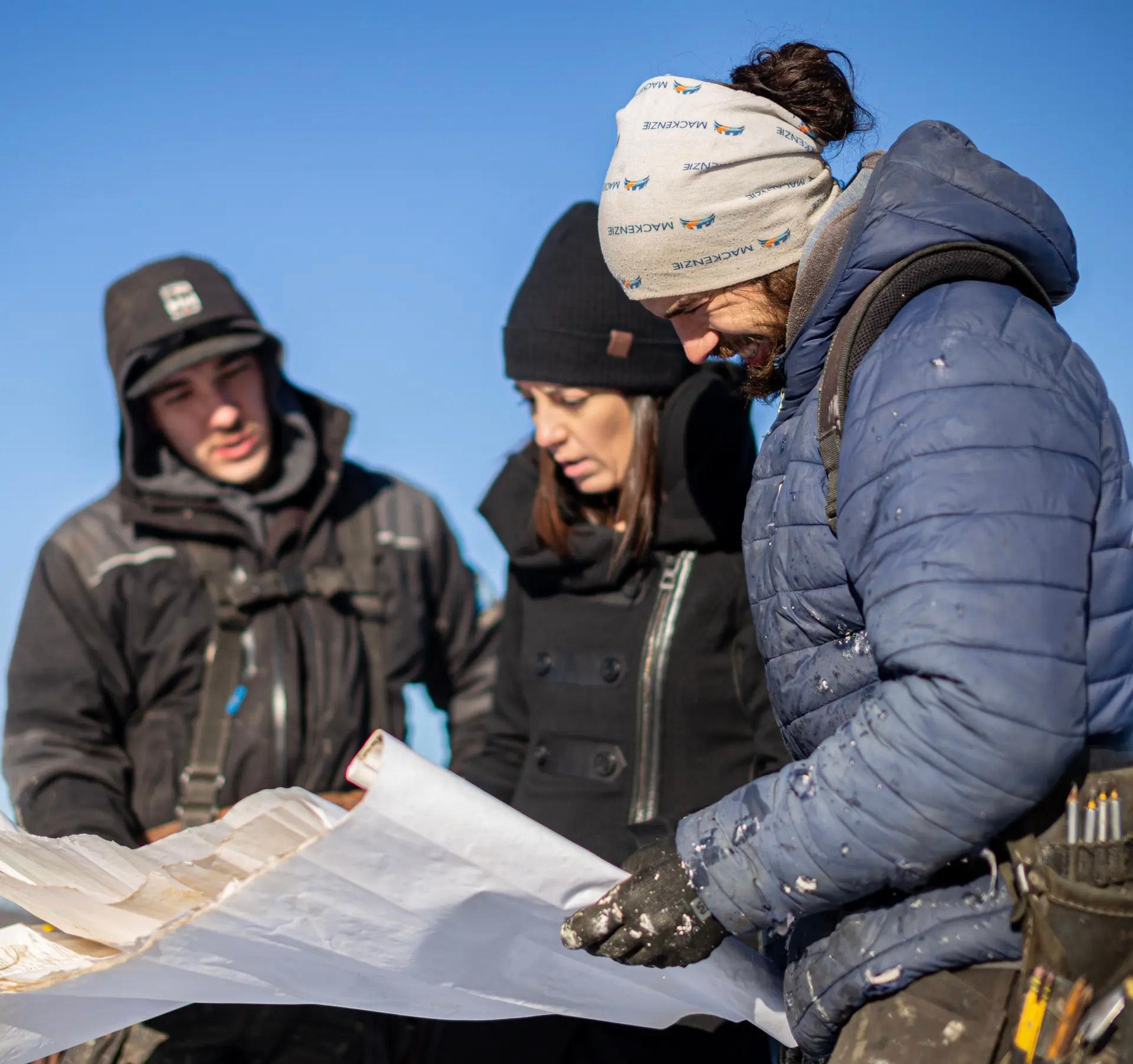 Équipe de professionnels de la construction examinant un plan de chantier sur un site en hiver.