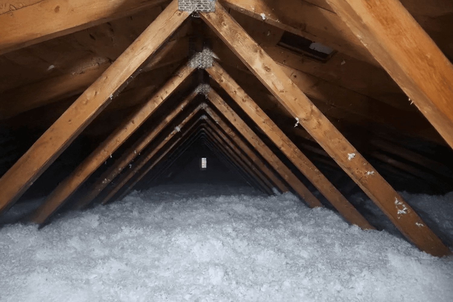 Grenier isolé avec de la cellulose soufflée sous une charpente en bois, assurant une protection thermique et acoustique.